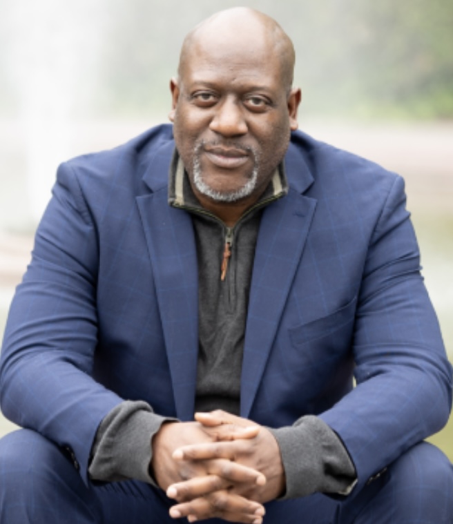 Tomike Ogugua seated outdoors in a blue suit
